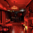 Cozy, dimly lit room with red lighting, featuring comfortable seating and candles, creating an inviting atmosphere for ghost tours and paranormal experiences.