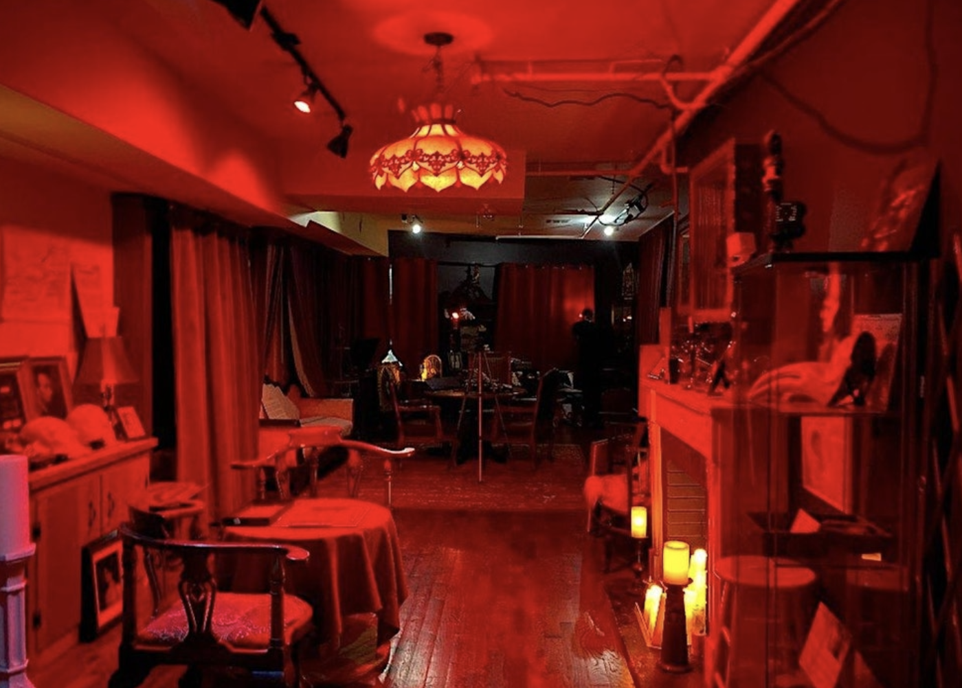 Haunted museum interior featuring dim red lighting, vintage furniture, and paranormal artifacts, enhancing the immersive ghost tour experience.