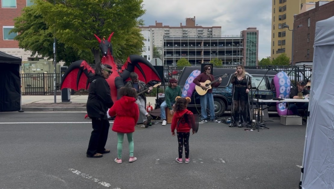 Jersey Devil Fable Festival musicians and performers with a large Jersey Devil mascot and attendees.