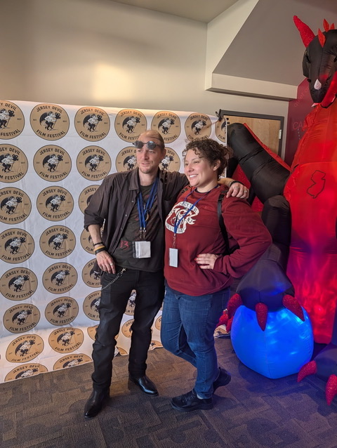 Jersey Devil Film Festival attendees and vendors posing with festival backdrop and Jersey Devil mascot.