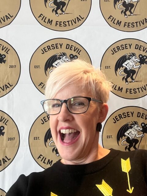 Jersey Devil Film Festival backdrop and smiling woman, celebrating festival success and community engagement.