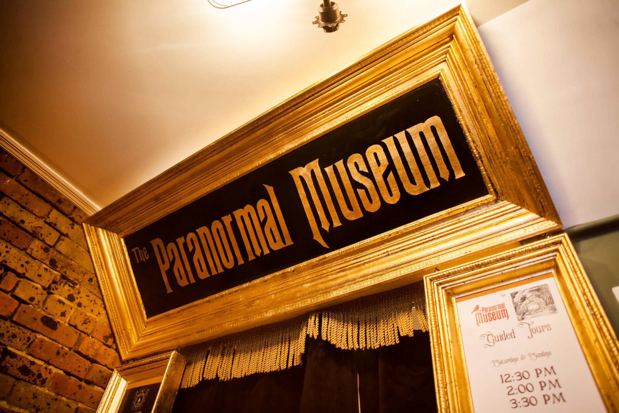 The Paranormal Museum sign and guided tours schedule in ornate gold frame.